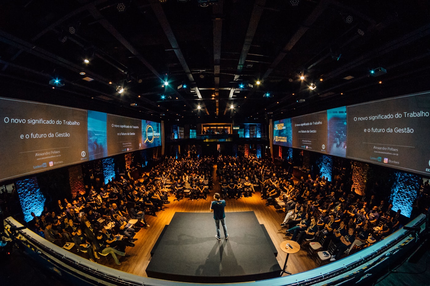 A speaker on stage presenting to a full room.